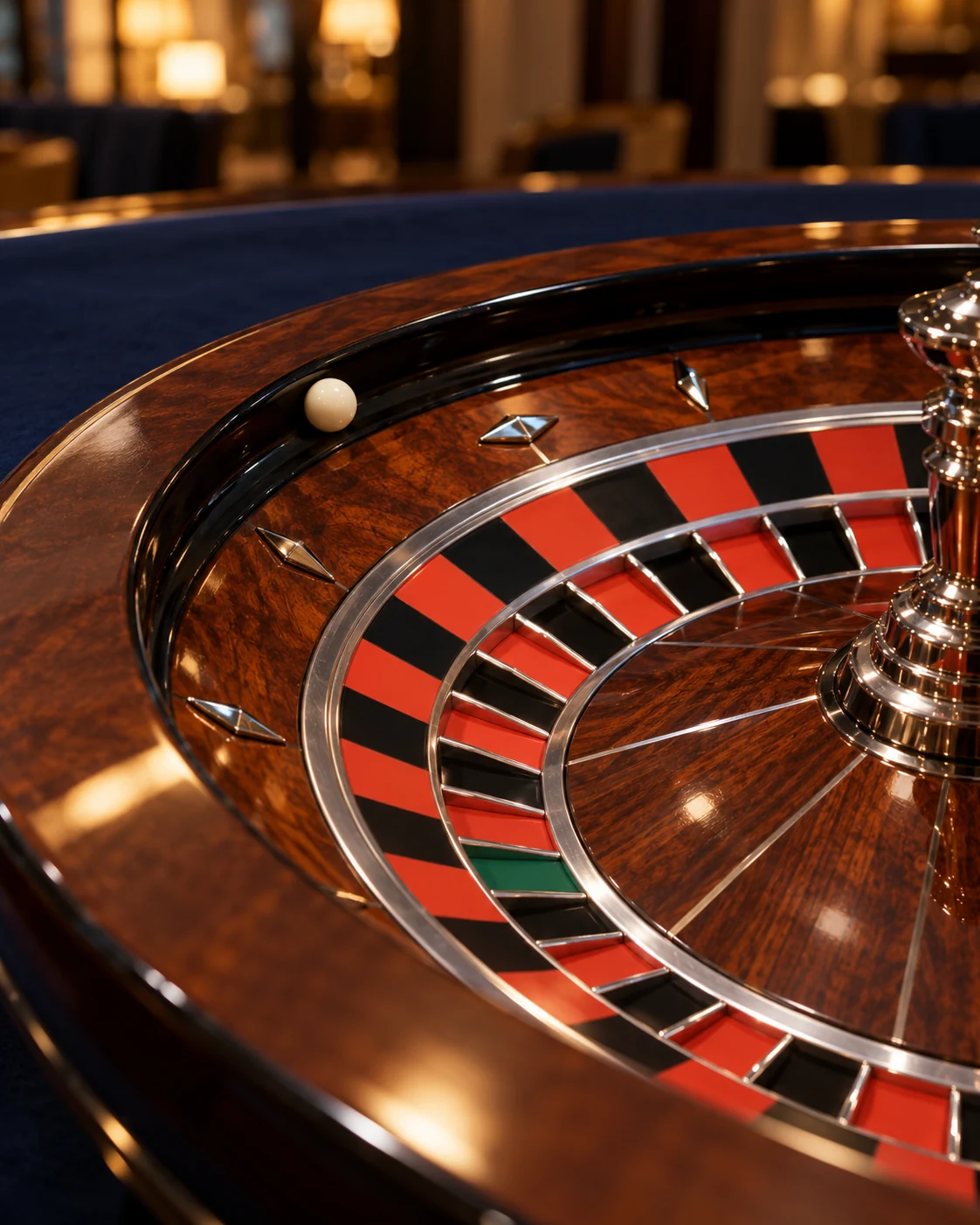 Wooden roulette wheel with an ivory-coloured ball beside blue felt.